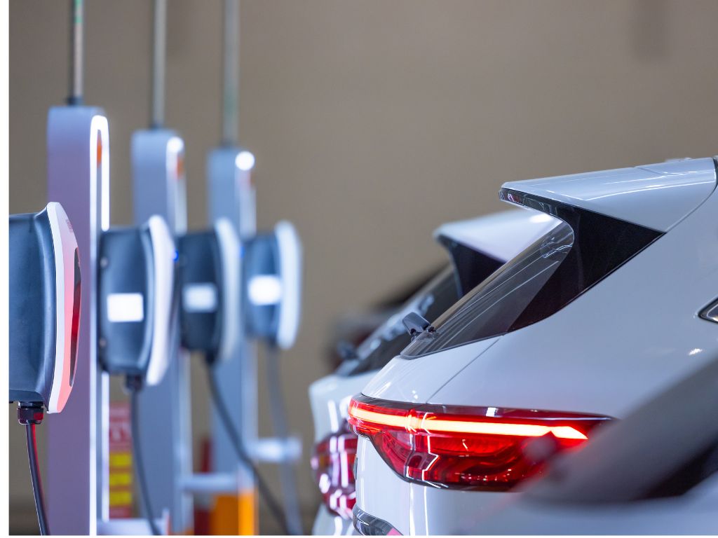 Vehículos eléctricos de una empresa cargando en estaciones de carga, evidenciando la electromovilidad corporativa.