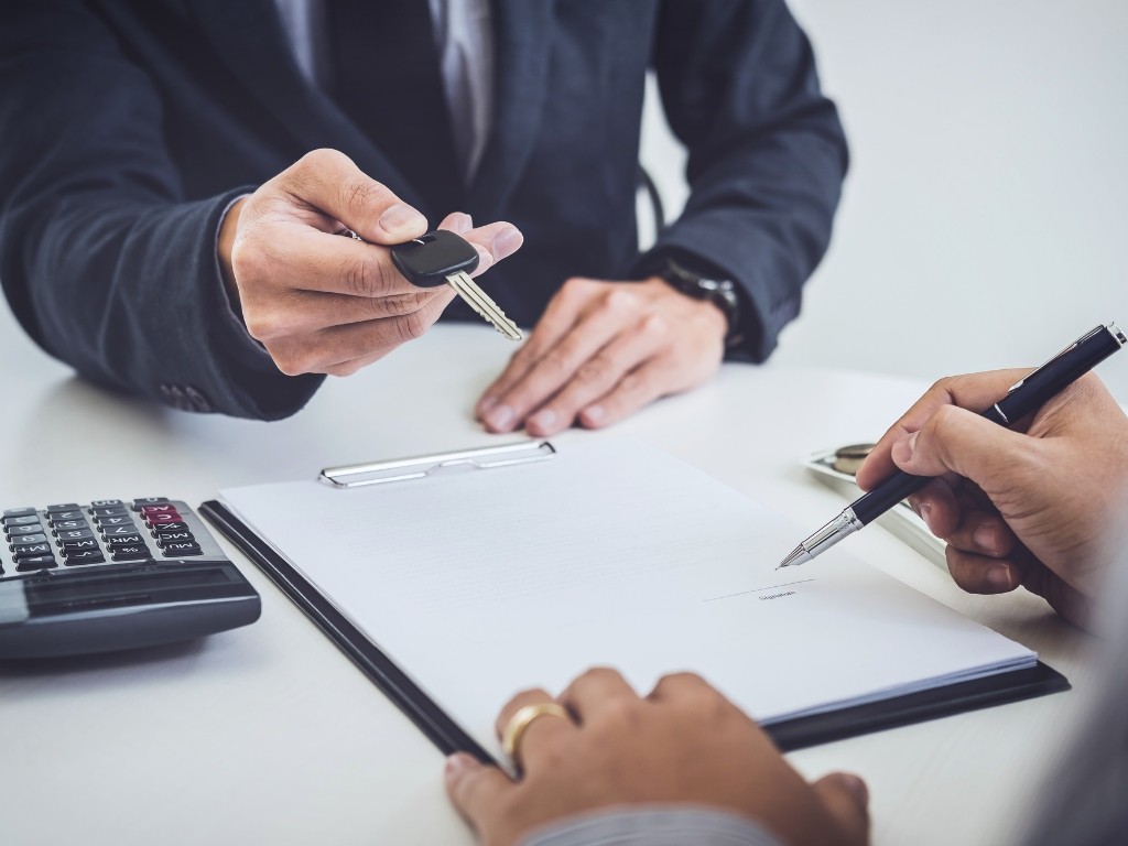 Firma de contrato y entrega de llaves tras firmar leasing operativo o crédito automotriz.